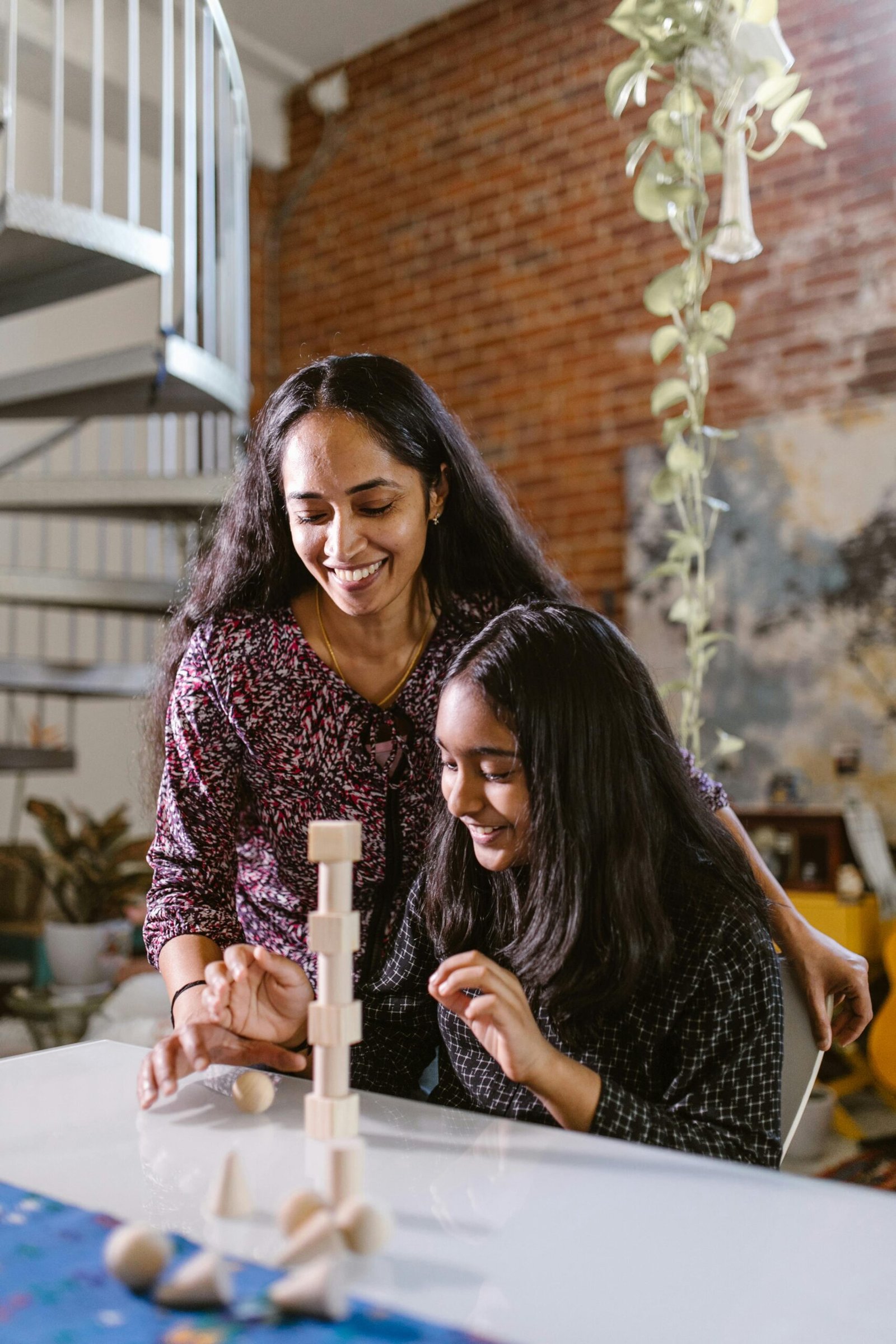 Mother and daughter enjoying building wooden blocks at home, fostering creativity and bonding.